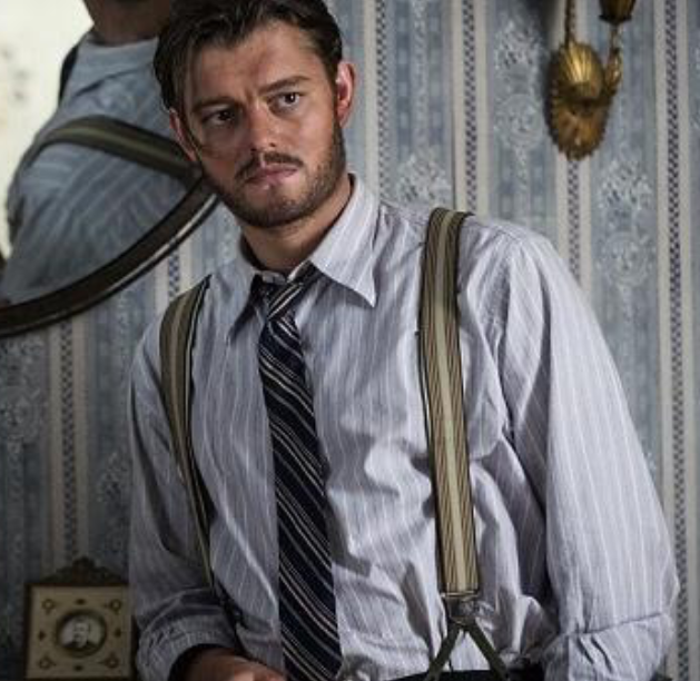 Character still — young officer in period shirt, tie and suspenders